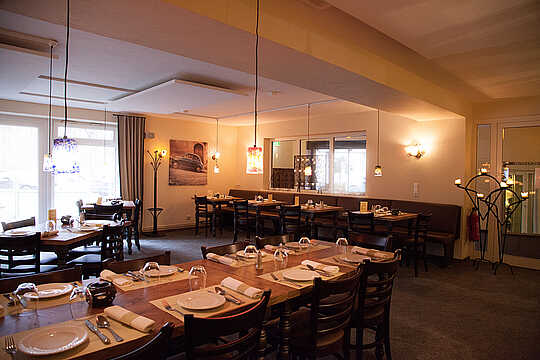 Benvenuto in dre Trattoria "del bosco" - Italiener im Hotel Munte am Stadtwald - Bremen Mehrere gedeckte Tische und Stühle in einem gemütlich beleuchteten Restaurant.